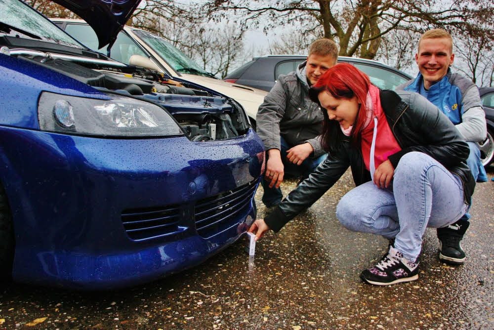 Melanie Markgraf demonstriert mit einer Zigarettenschachtel, wie tief der Astra Caravan von Daniel Nürnberger (li.) gelegt ist. Rechts im Bild: Florian Herzau aus Querfurt.