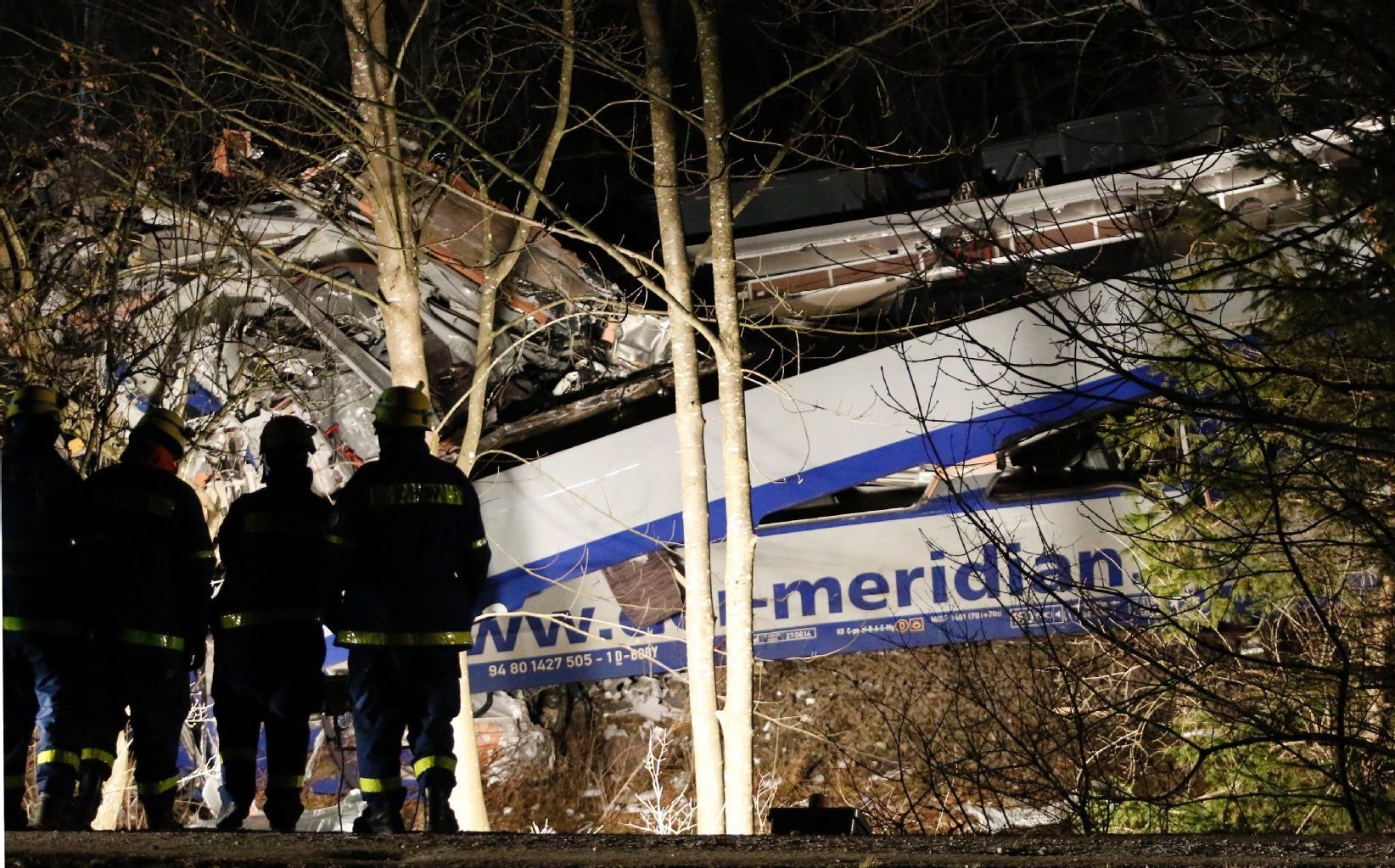 Helfer des Technischen Hilfswerkes beobachten in Bad Aibling die Bergearbeiten unter Flutlicht.