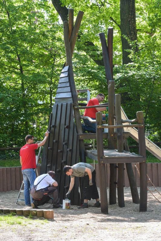 Die Helfer versiegeln das Holz des Klettergerüsts mit einem speziellen Anstrich. Auf zwei Spielplätzen in Köthen haben sie die Arbeiten durchgeführt.