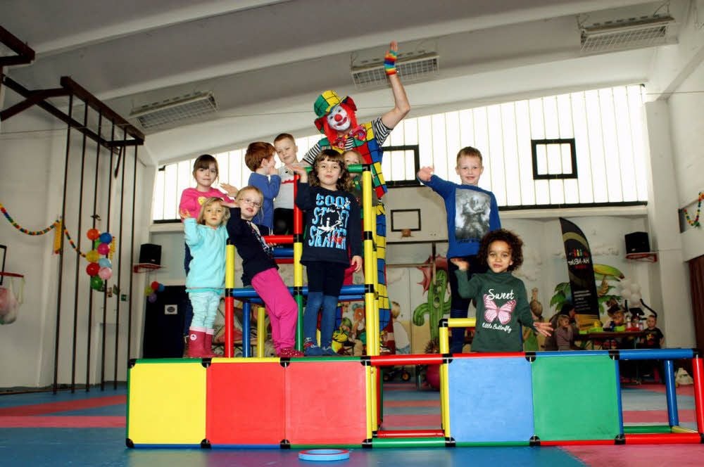 Kinder der Kita „Fuchs und Elster“ erklimmen zusammen mit Clown Lulo das Klettergerüst.