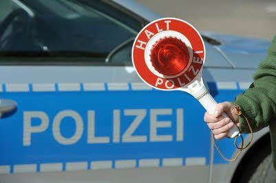 Ein Einsatzwagen der Polizei und eine Polizeikelle.