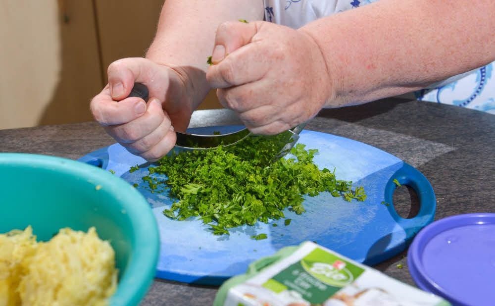 Marion Henning ist von Beruf Köchin. Entsprechend routiniert geht sie in der Küche zu Werke - egal ob beim Einfüllen der Brühe, dem Zerkleinern von Petersilie oder dem Kneten des Kloßteiges. Angerichtet sieht die Brühe mit Klößen und frisch geriebenem Meerrettich mehr als lecker aus.