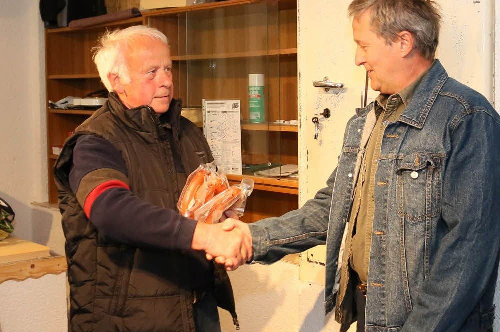 Vereinschef Werner Linke überreicht an „Bratwurstkönig“ Thomas Richmann gleich drei der leckeren Bratwürste.