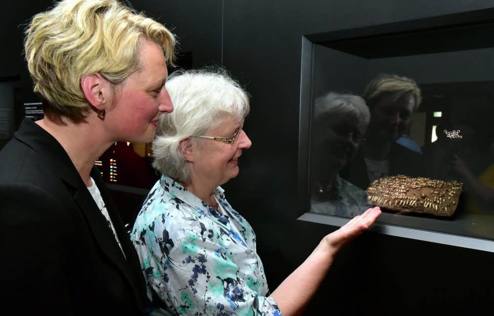 Besucherinnen der Ausstellung betrachten die Handtasche aus Hundezähnen.