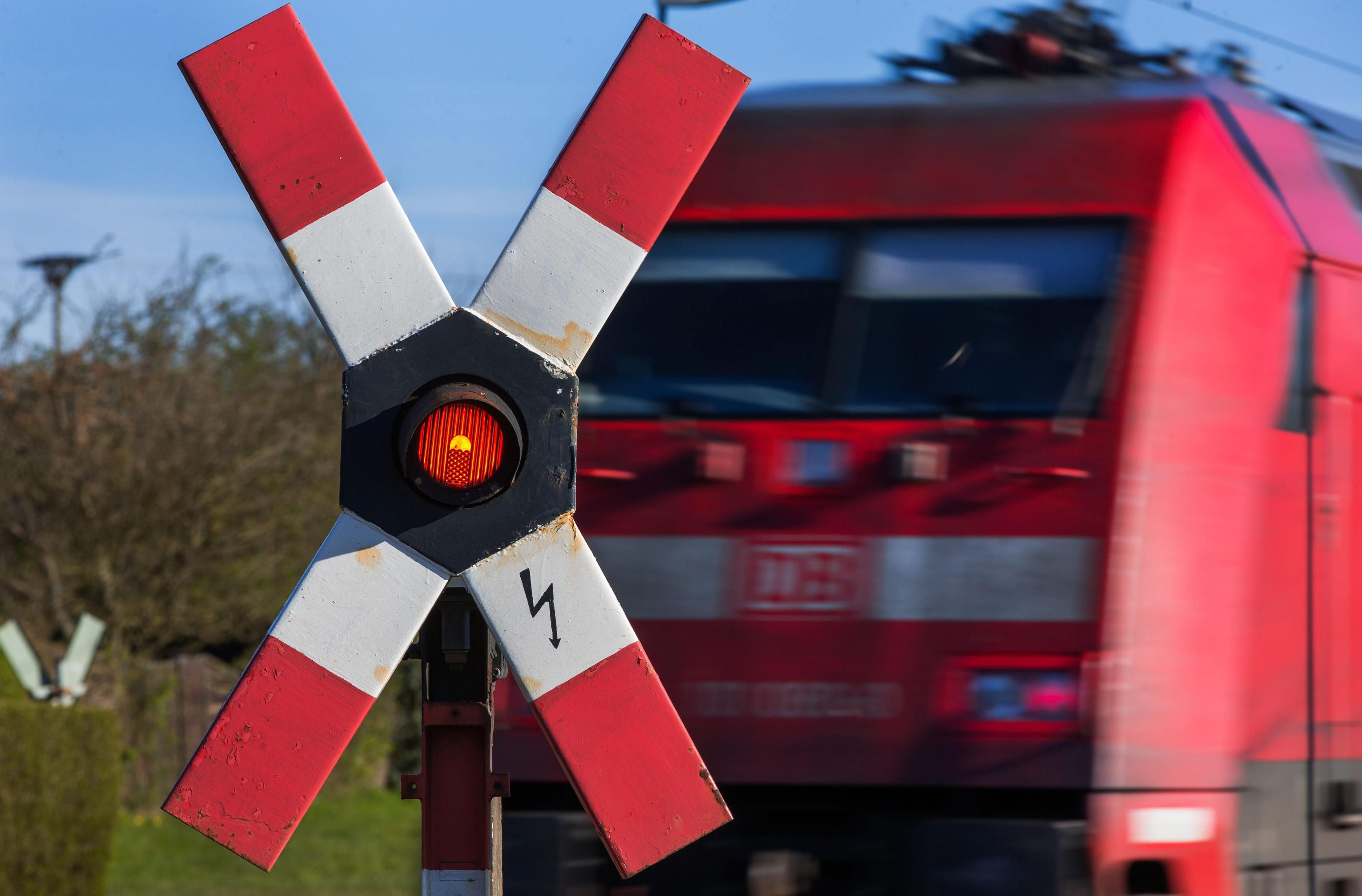 Ein Zug der Deutschen Bahn passiert an einem Bahnübergang ein Andreaskreuz.