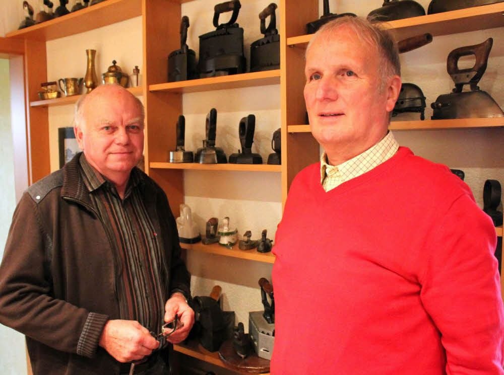 Die beiden Bergwitzer Ortschronisten Herbert Hoch (links) und Georg Kilz stehen hier vor der Bügeleisensammlung, die eine Liedenschaft von Herbert Hoch ist.