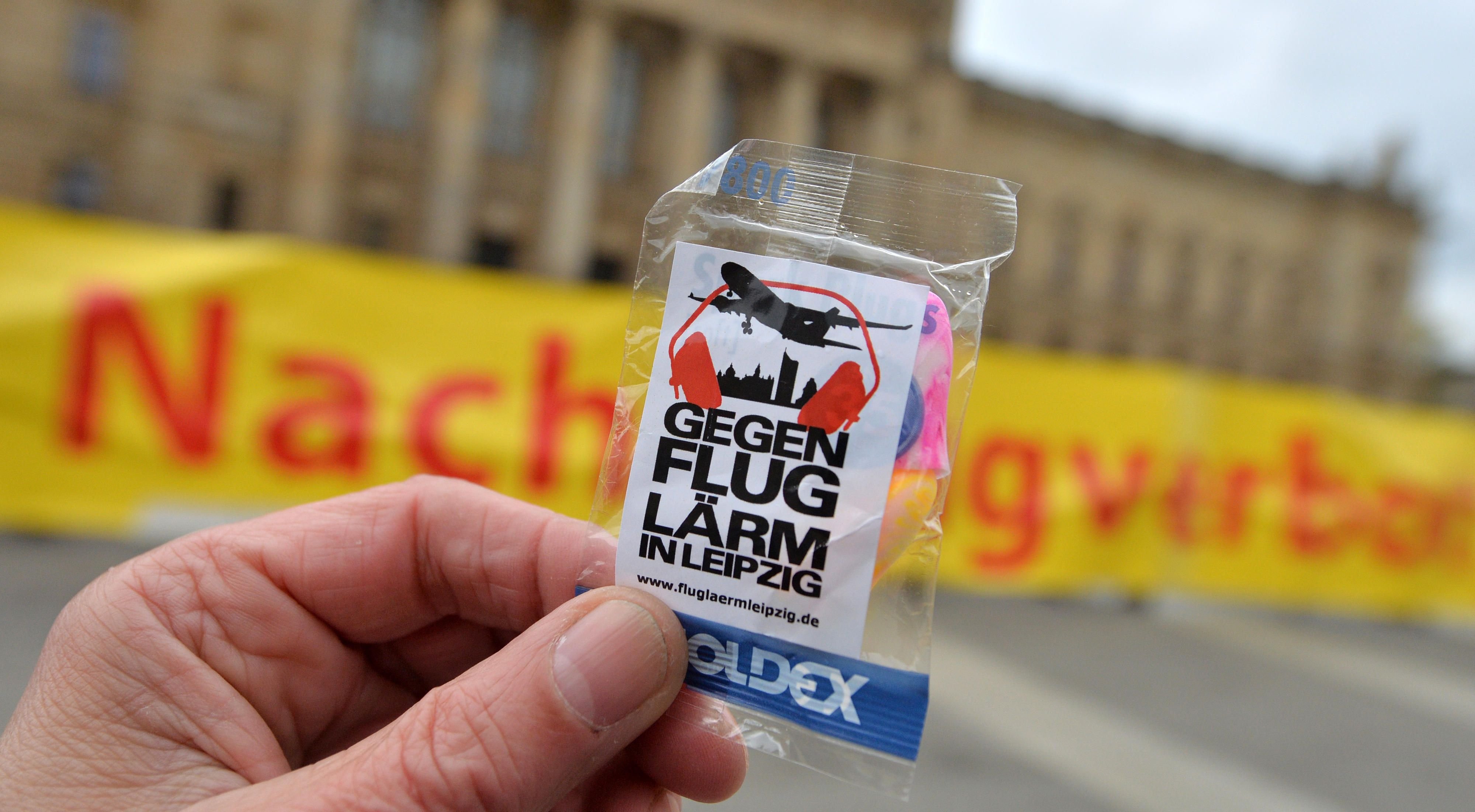Mit einem Transparent und Gehörschutz fordern verschiedene Bürgerinitiativen und Interessengemeinschaften vor dem Bundesverwaltungsgericht in Leipzig ein Nachtflugverbot.