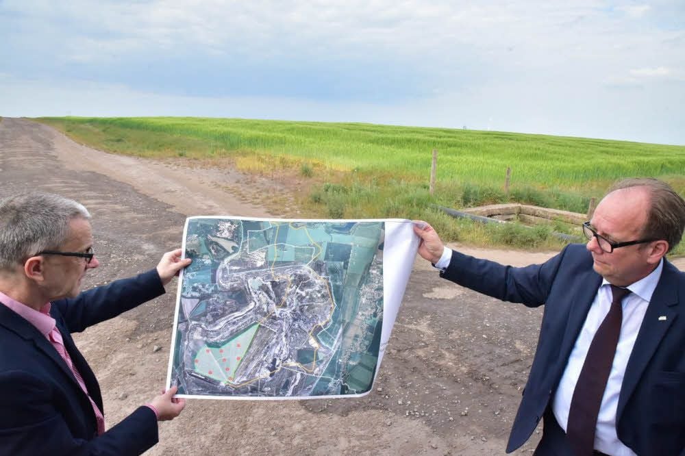 Auf der Fläche im Hintergrund soll ein Teil des Energieparks Profen entstehen. Norbert Claus aus dem Bereich Öffentlichkeitsarbeit und Mibrag-Direktor für Bergbauentwicklung Andreas Günther zeigen den Plan für den Park auf dem Bergbaugelände.