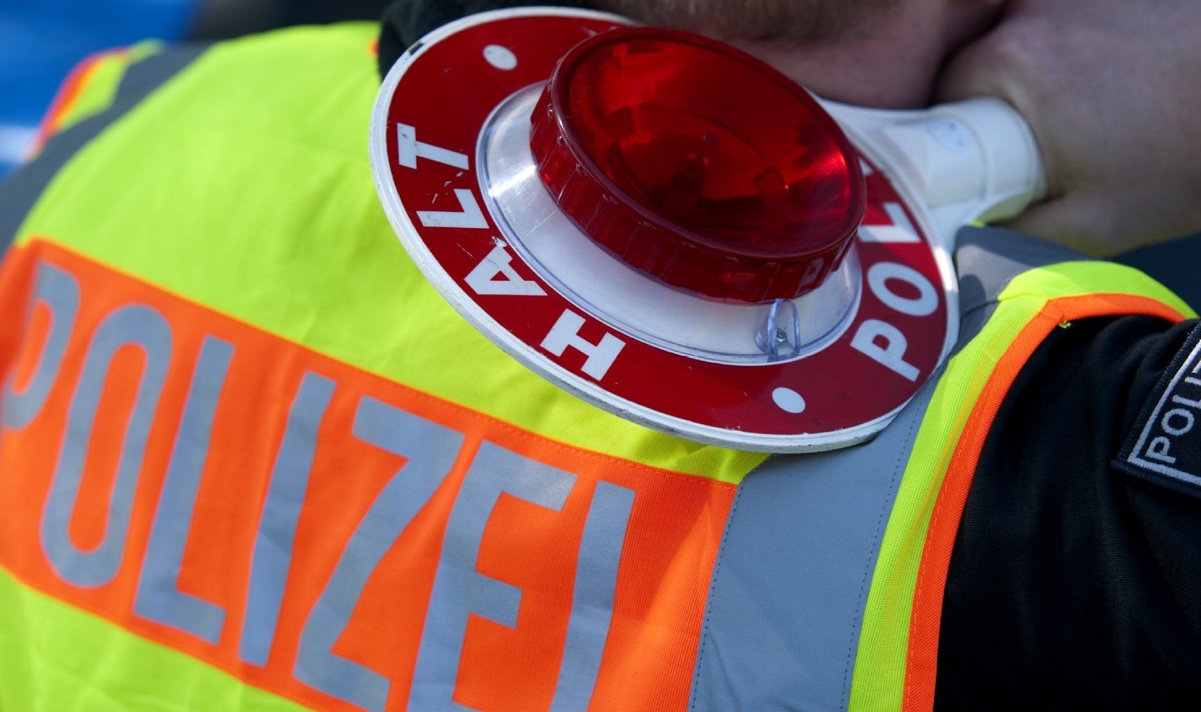 Verkehrskontrolle: Ein Polizist mit Warnweste und einer Polizeikelle.