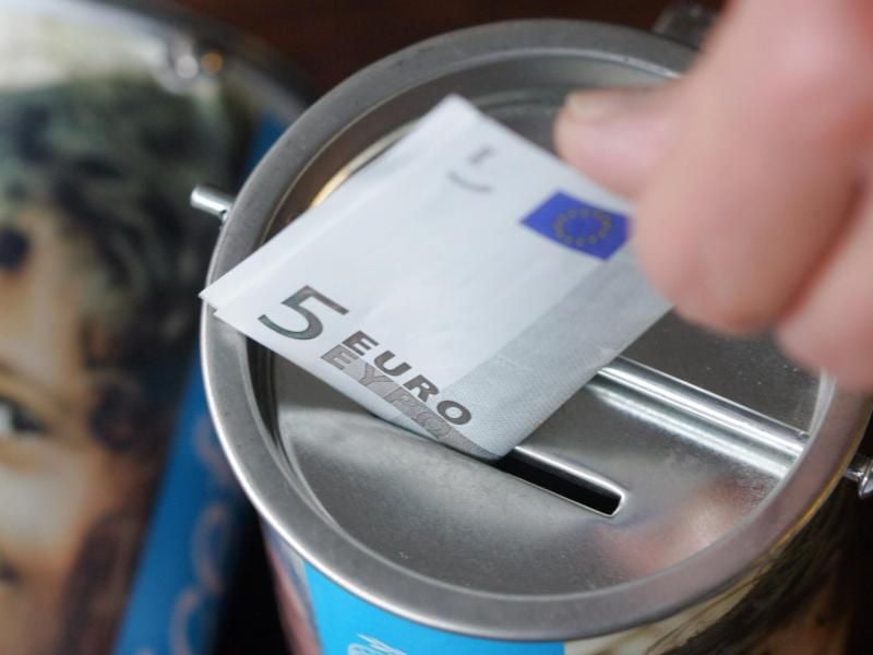 Ein Fünf-Euro-Schein wird in eine Spendendose gesteckt. Foto: Bernd Thissen/Archiv