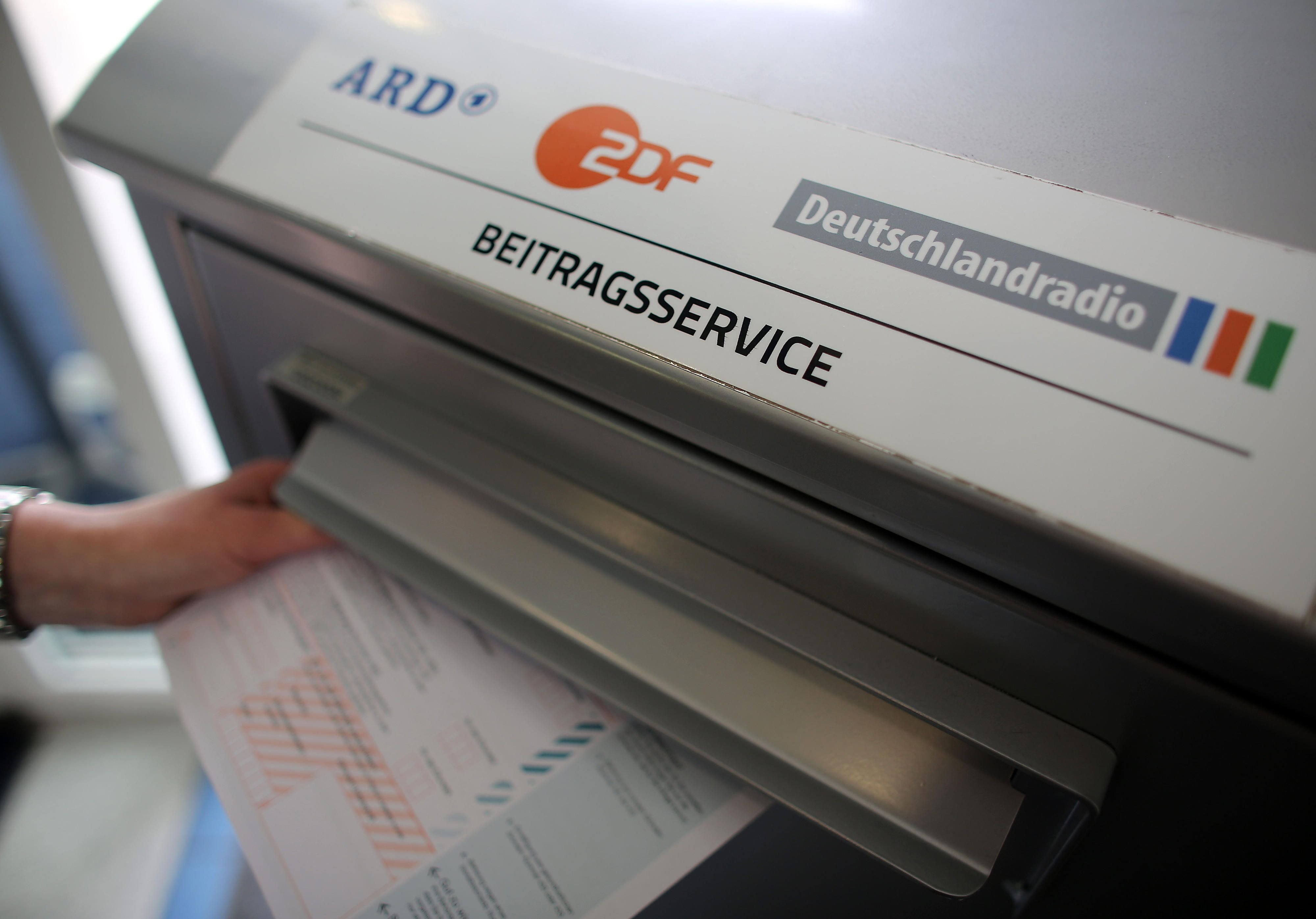 Eine Frau wirft beim Beitragsservice von ARD, ZDF und Deutschlandradio einen Fragebogen in den Briefkasten.