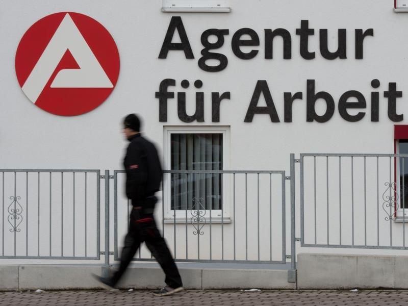 Passant vor dem Logo der Agentur für Arbeit. Foto: S. Kahnert/Archiv