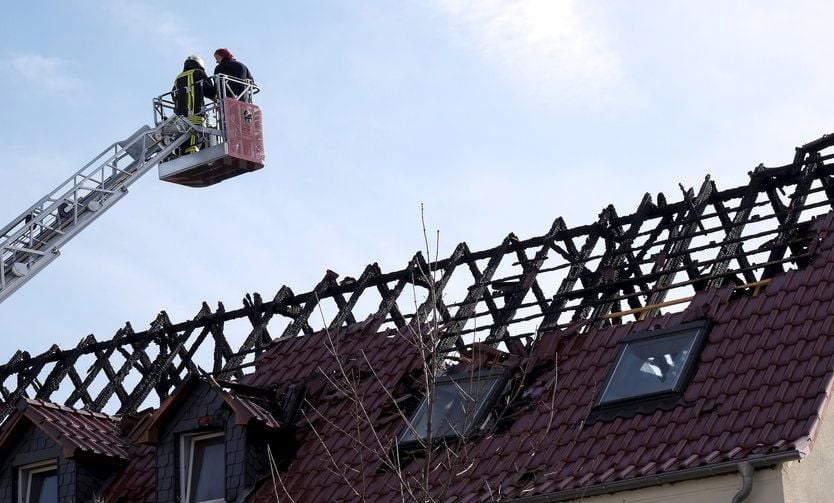 Einsatzkräfte der Feuerwehr begutachten am Ostersamstag des vergangenen Jahres das ausgebrannte Dachgeschoss jenes Tröglitzer Hauses, in dem40 Flüchtlinge untergebracht werden sollten. Die Flammen loderten in der Nacht zum 4. April.