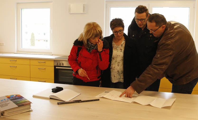 Vorstandsmitglieder der Wohnungsgenossenschaft und der Geschäftsführer des Kranken- und Pflegedienstes Wend schauen sich mit einer Mitarbeiterin einer Einrichtungsfirma Unterlagen an.