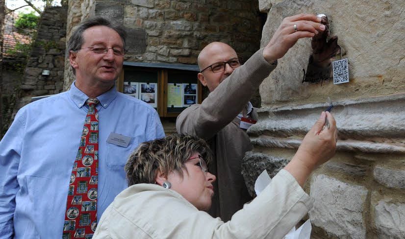 Günther Saken (l.), Jan Scheunemann und Kerstin Bullerjahn befestigen die Luther-Plakette am Eingang zum Schloss in Seeburg.