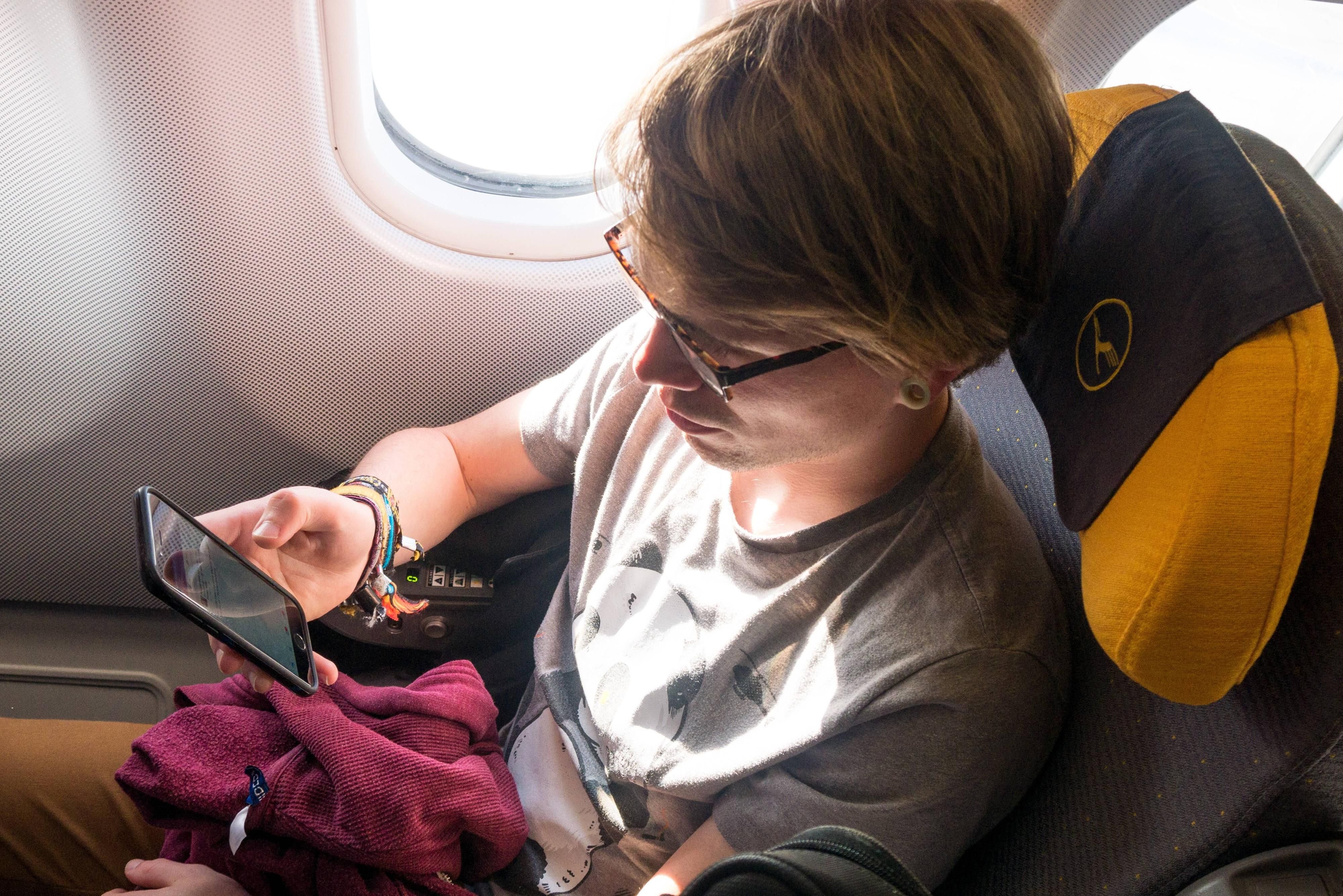 Symbol-Bild: Fluggast nutzt sein Smartphone an Bord eines Airbus A340 der Lufthansa