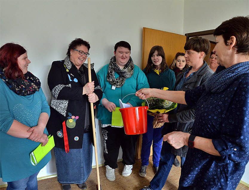 Gabriele Mück überreicht zur Schlüsselübergabe an Uliana Radtke (2.v.l.) Eimer und Besen.