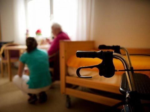 Eine Mitarbeiterin eines Pflegedienstes spricht mit einer Seniorin.