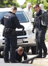 Polizisten suchen in Dessau-Roßlau an einem Gully auf einer Straße nach Spuren.