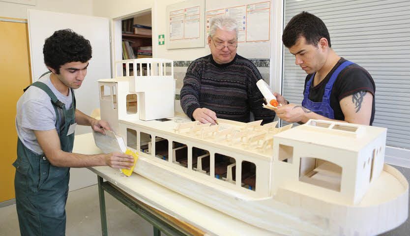 Omar, Bernd Kallies und Mojib (v.l.) bauen an dem Schiff.