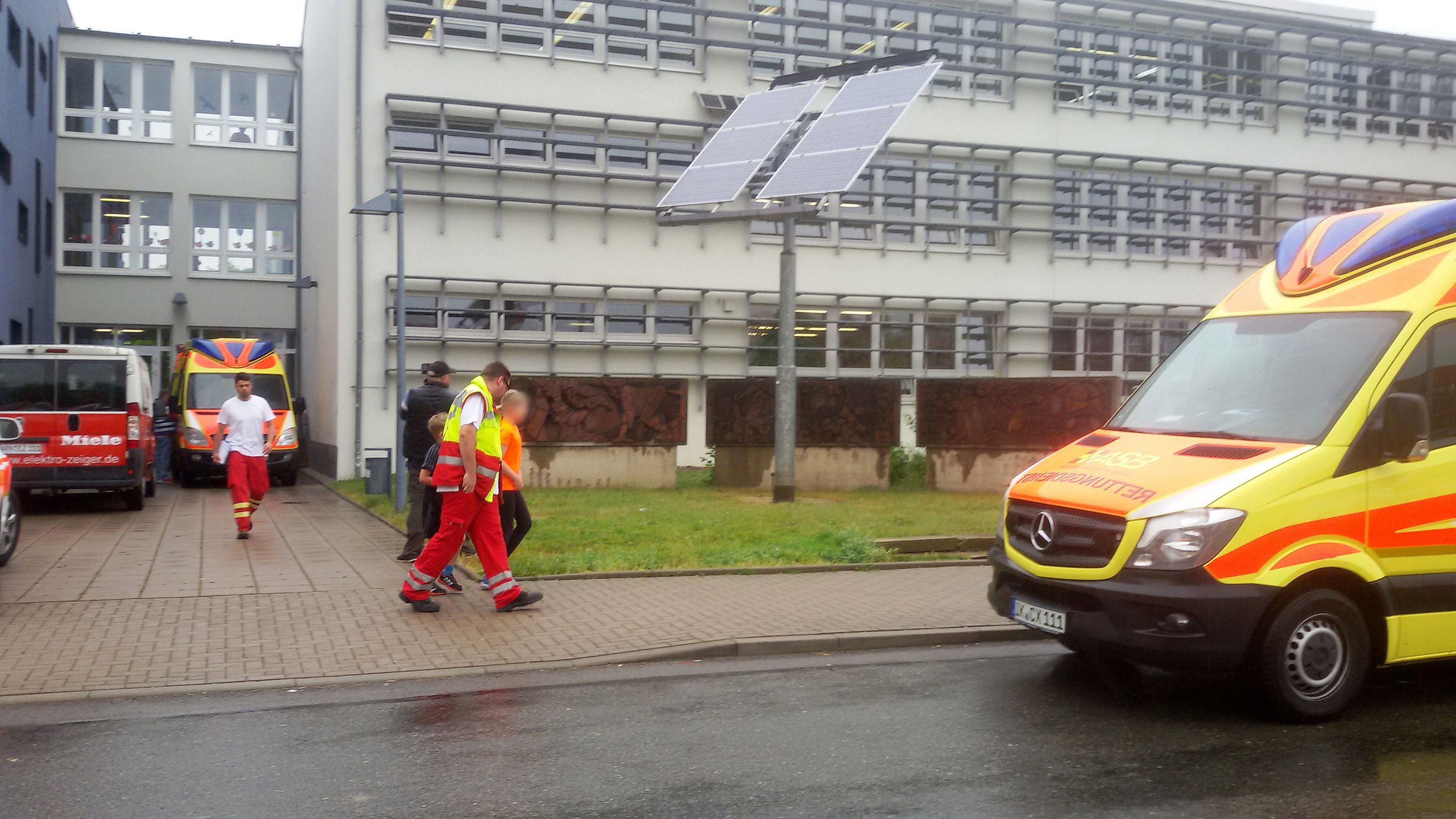 Ein Notarzt geht mit zwei Schulkindern vor einer Schule in Arnstadt zu einem Rettungswagen.