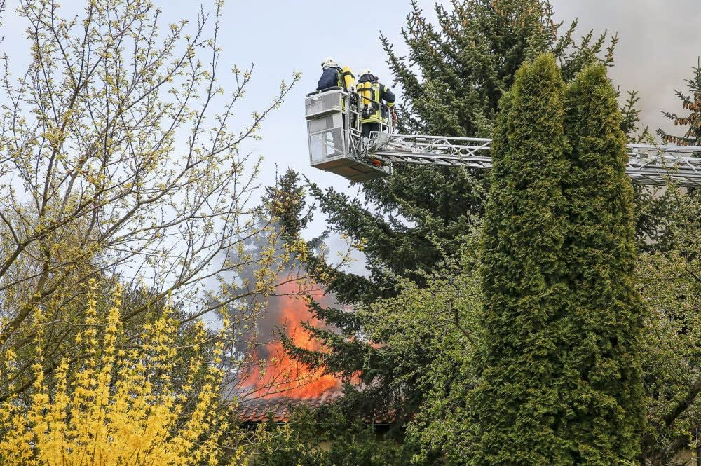 Mit einer Drehleiter versuchen Einsatzkräfte der Feuerwehr zum Dachstuhl des Hauses zu gelangen, um den Brand zu löschen.