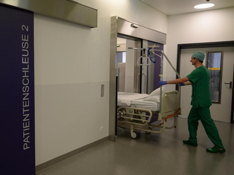 Ein Pfleger schiebt im Krankenhaus ein Bett in den Operationstrakt. Foto: Patrick Seeger/Archiv