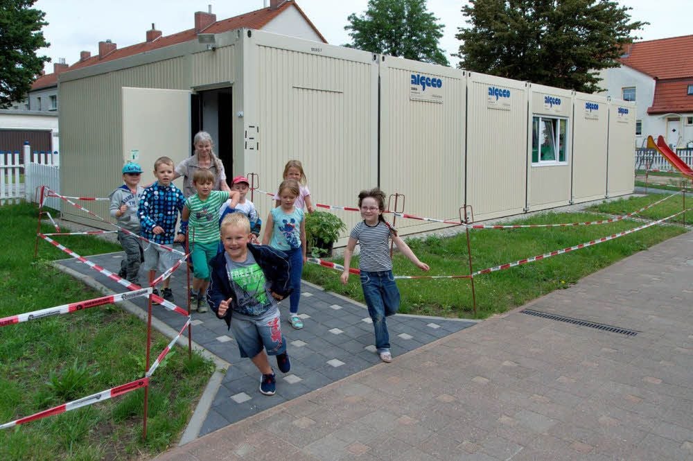 Die Kinder und Leiterin Silvia Hoffmann vor dem Container