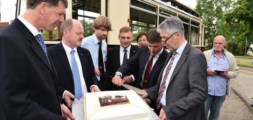 Ille-Geschäftsführer Andreas Plehn schneidet zur Feier des Tages die Torte der Bäckerei Graupner an, auf der der Triebwagen zu sehen ist.
