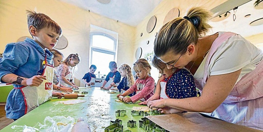 Caroline Kopelke vom Elternkuratorium (rechts) unterstützt die Drei- bis Sechsjährigen beim Backen in der Kinderlernküche.