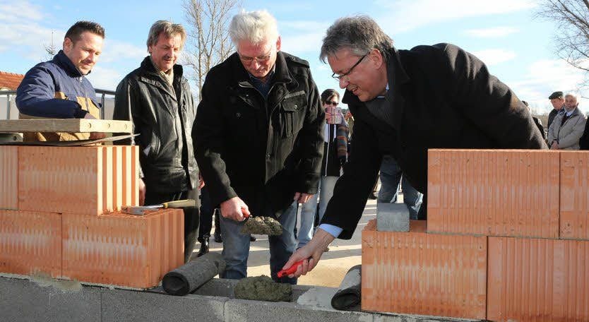 Oberbürgermeister Robby Risch und Ortsbürgermeister Wolfgang Kurtze (v.re.) mauern die Hülse ein.
