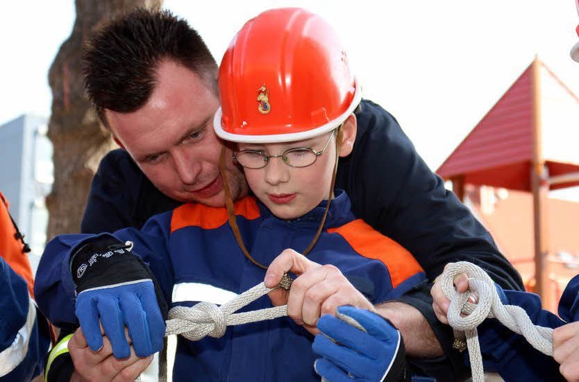 Der stellvertretende Wehrleiter Florian Worg übt mit dem jungen Feuerwehrmitglied Robin einen Knoten.