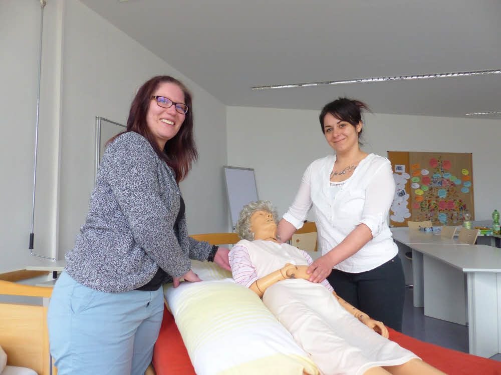Stefanie Ziebarth (links) und Juliana Reuthe üben in der Berufsfachschule an einer Puppe den Umgang mit pflegebedürftigen Menschen.