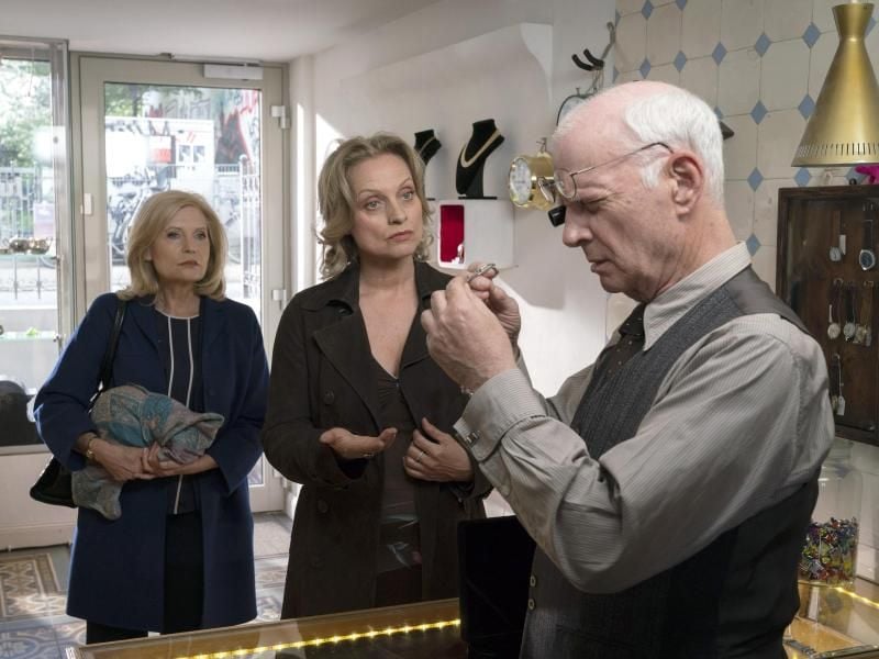 Isa von Brede (Sabine Postel, l.) hilft dem befreundeten Uhrmacher Jannik Brodersen (Peter Meinhardt). Seine Kundin Gerda Sahling (Catherine Flemming) beschuldigt ihn, ihr Schmuckstück durch eine billige Imitation ersetzt zu haben. Foto: ARD/Georges Pauly