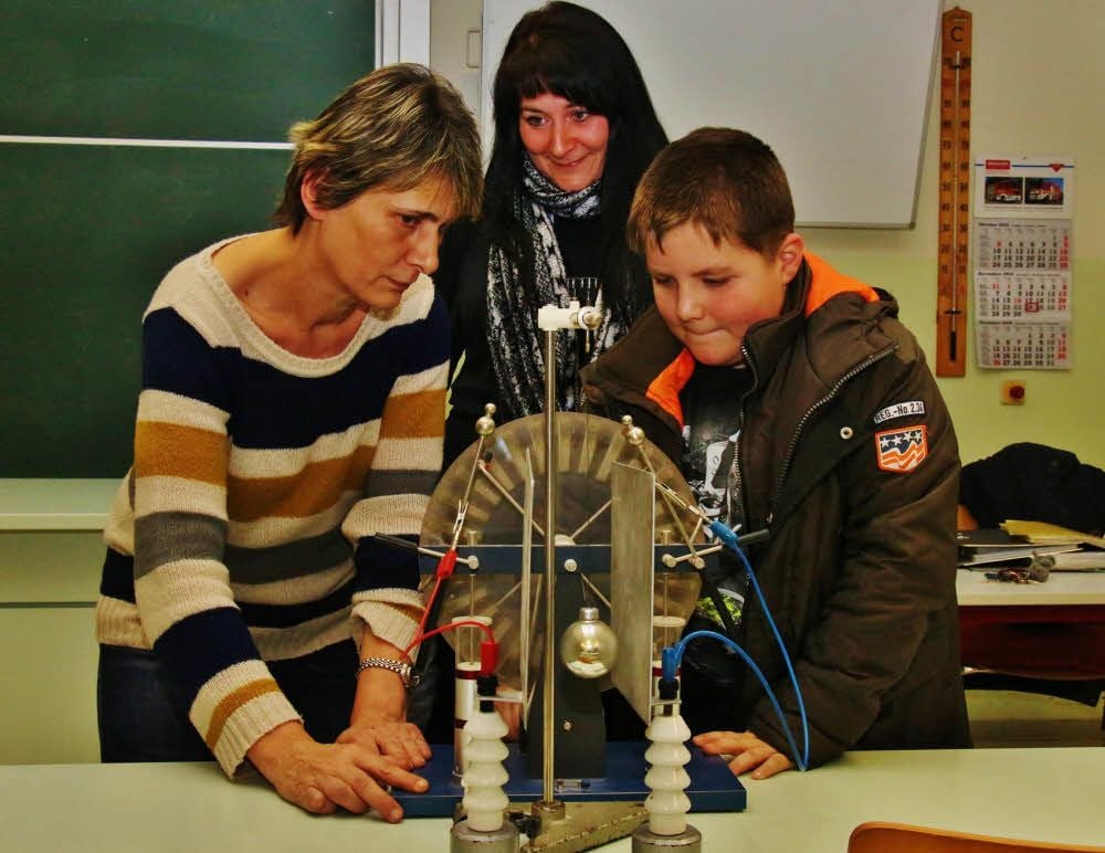 Nick und Yvonne Bürger lassen sich von Physiklehrerin Kerstin Baumann die Funktionsweise einer Influenzmaschine erklären.