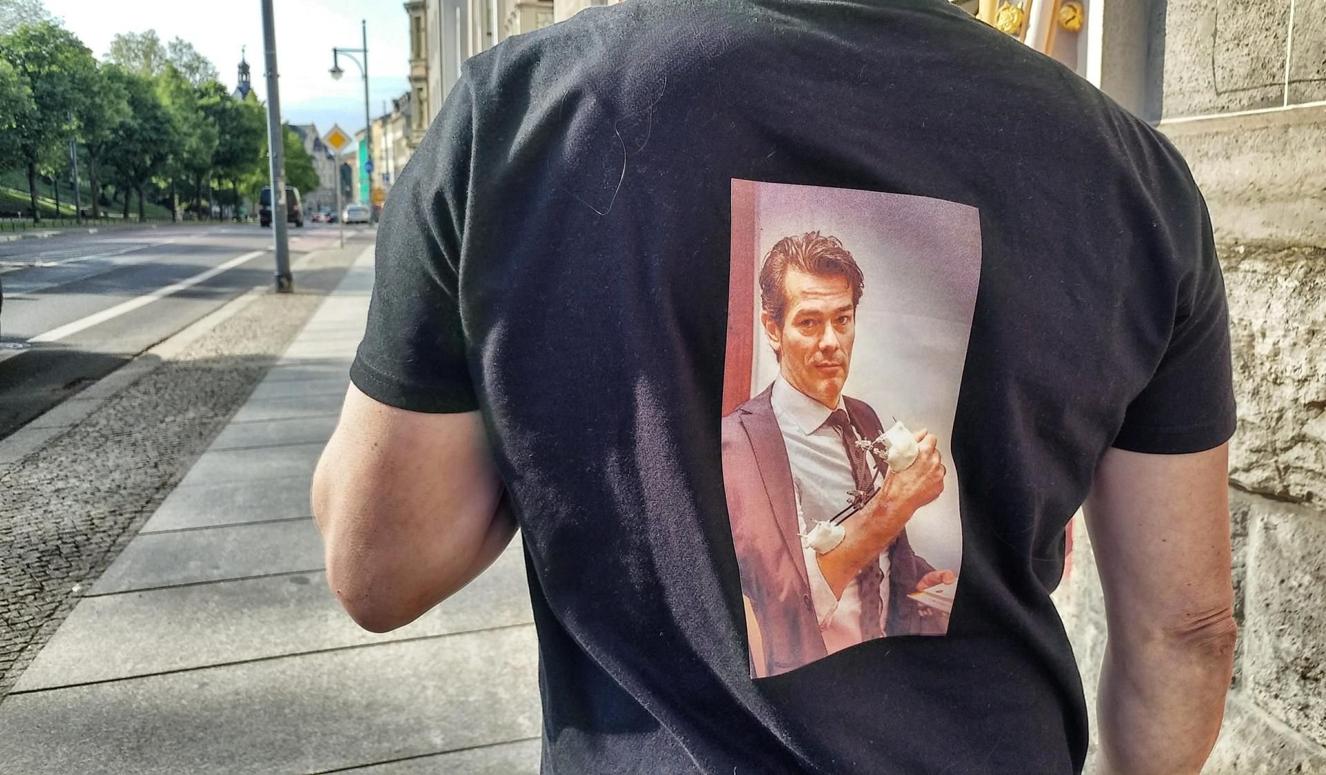 Ein Mann trägt ein T-Shirt mit dem aufdruckten Foto des selbst ernannten Staats- und Religionsgründers Adrian Ursache aus Reuden. Offenbar hat dieser auch Fans.