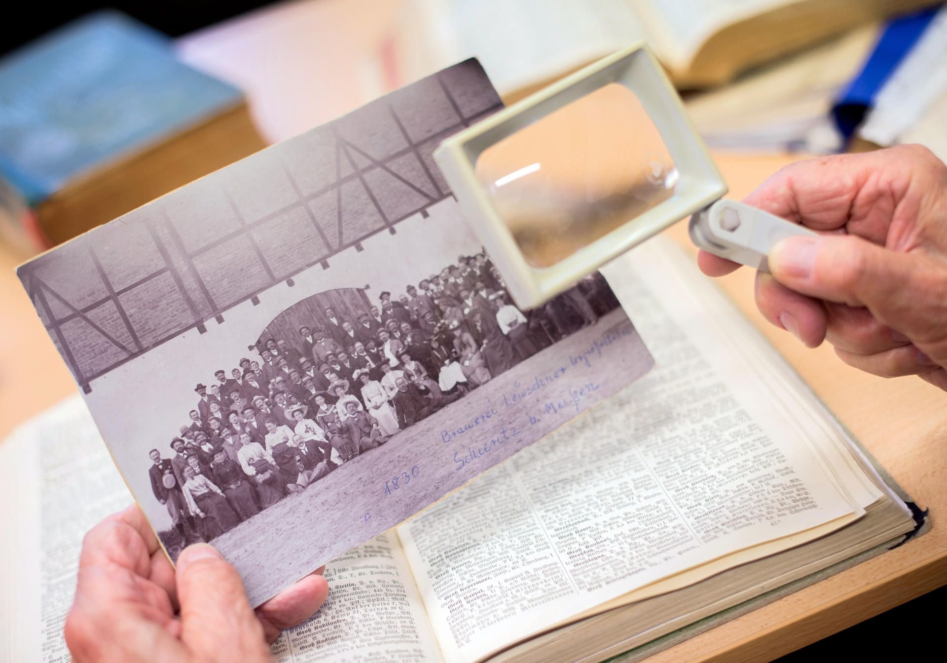 Ein Mann sucht auf einem historischen Foto nach möglichen Vorfahren.