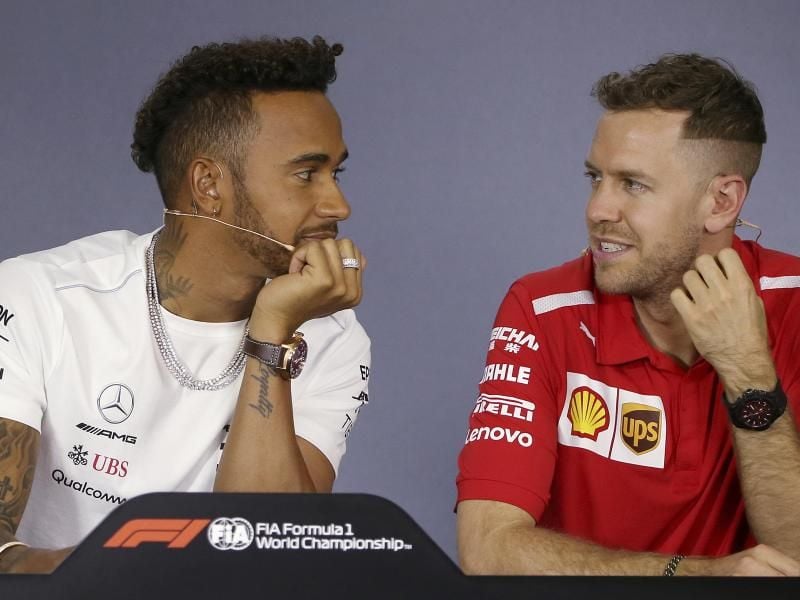 Lewis Hamilton (l) und Sebastian Vettel auf einer Pressekonferenz im Gespräch. Foto: Rick Rycroft/AP