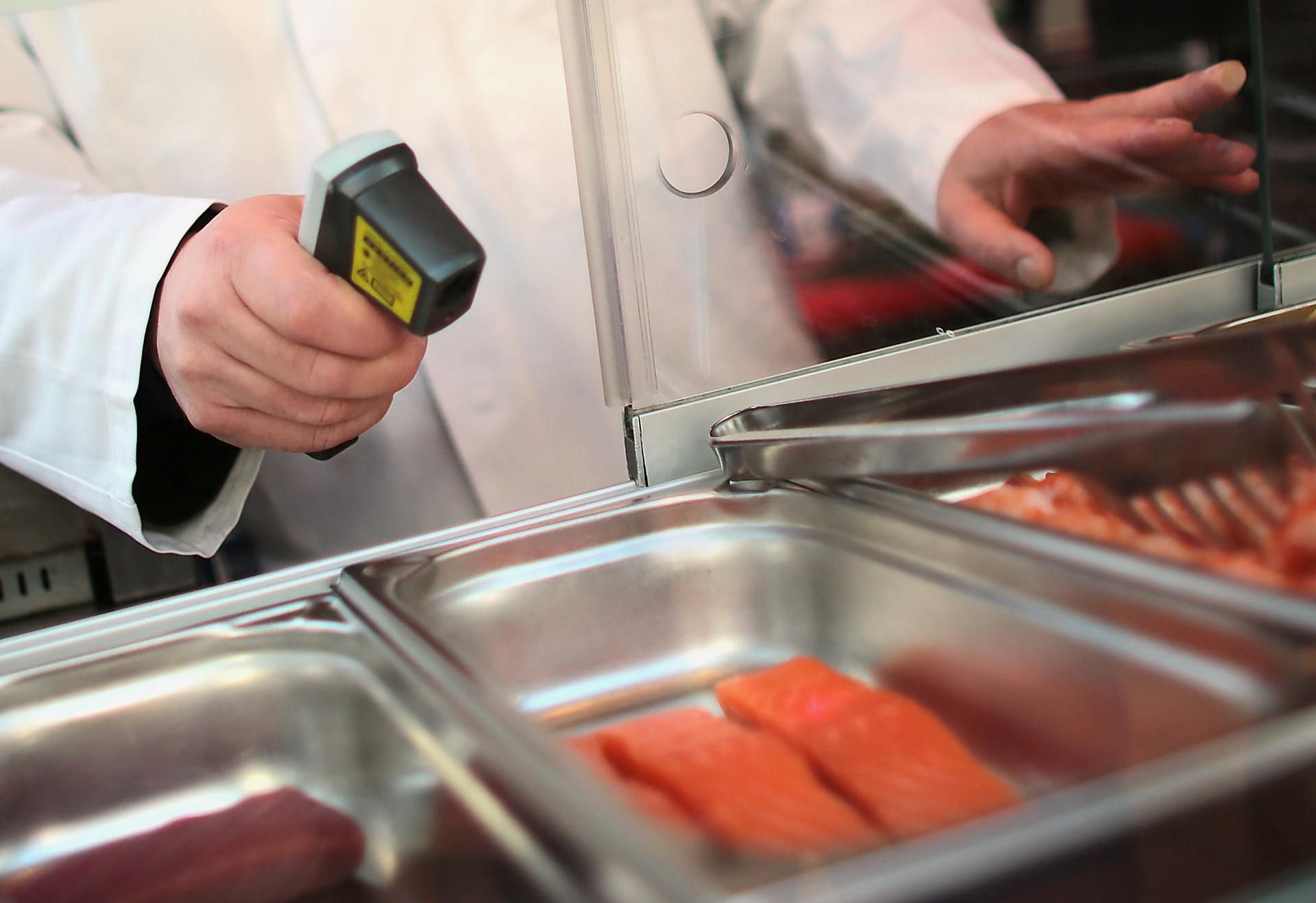 Wie gut ist unser Essen? Ein Lebensmittelkontrolleur misst die Temperatur von Lachsfilets.
