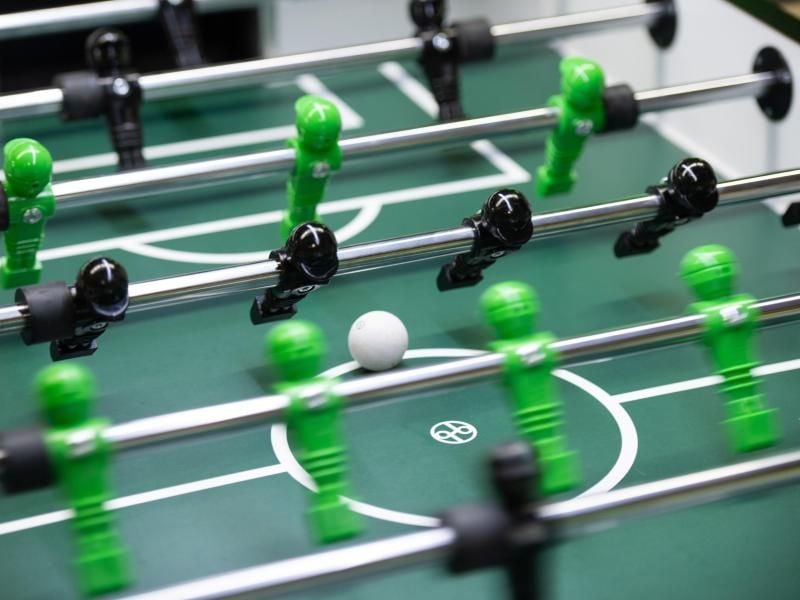 Tischfußballfiguren bewegen sich an ihren Stangen. Foto: Daniel Reinhardt/dpa