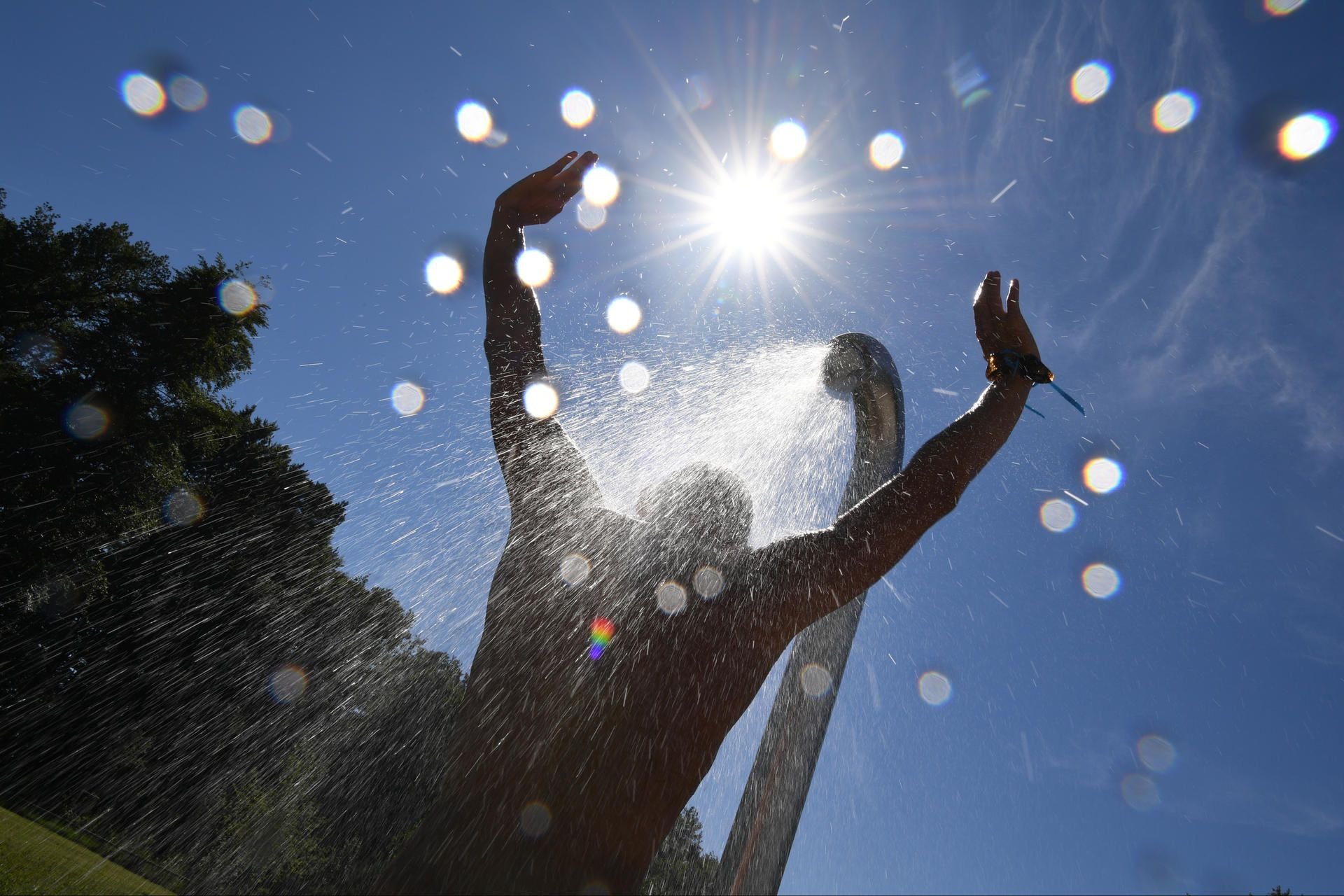 Sommer, Sonne, Hitze: Besucher eines Freibades erfrischt sich unter einer Dusche.