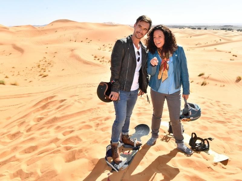 Hanna Liebhold (Barbara Wussow) ist es gelungen, Kapitän Max Parger (Florian Silbereisen) zu einem "Skiausflug" in die goldenen Sanddünen zu überreden. Foto: Dirk Bartling/ZDF/dpa