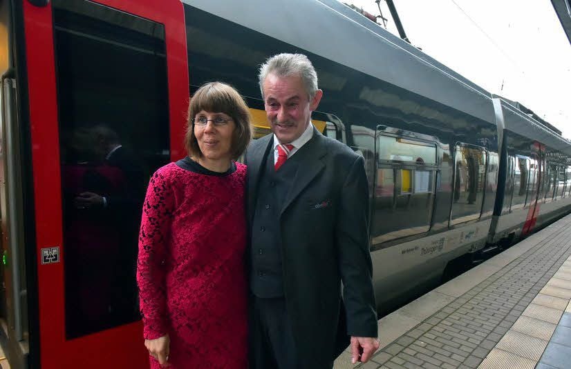 Das Paar posiert vor seinem Hochzeitszug.