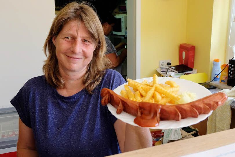 Riesen-Currywurst mit Pommes ist neben kalten Getränken der Renner am See. Imbiss-Chefin Annett Bosse serviert das Essen mehrmals am Tag.