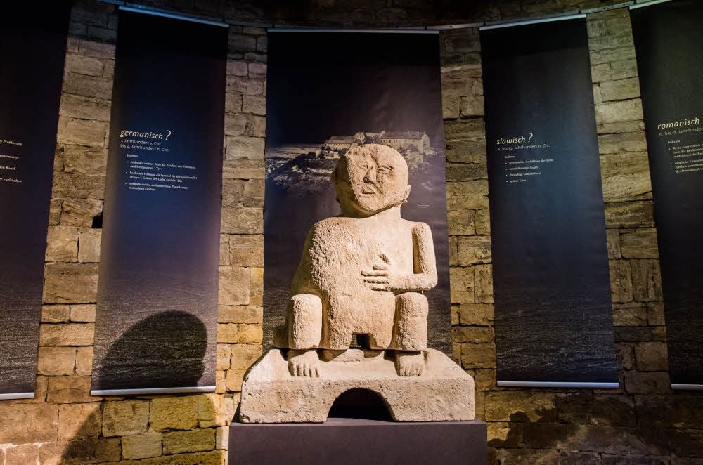 Symbolfigur der Ausstellung im Bergfried der Neuenburg ist der „Haingott“, eine Steinfigur, die seit über 500 Jahren unterm Dach des romanischen Wohnturms thront, vermutlich aber weit älter ist. Anhand unterschiedlicher Deutungen werden Zeugnisse einstiger Glaubenswelten gezeigt.