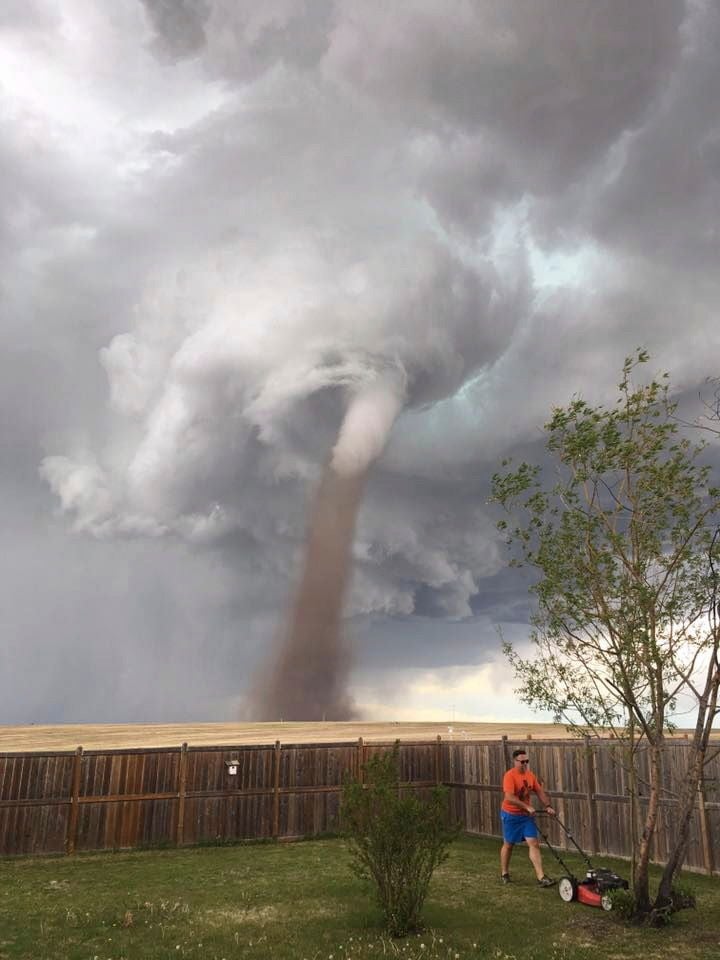 Theunis Wessels mäht seinen Rasen in Three Hills, Kanada, während ein Tornado im Hintergrund wirbelt.