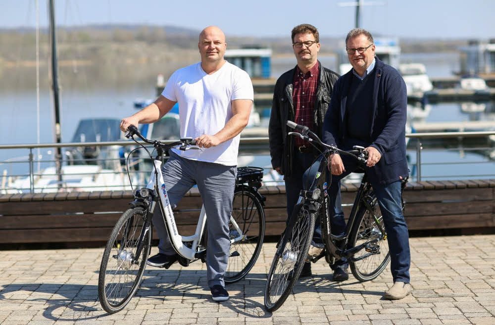 Der Geschäftsführer der Marina Mücheln GmbH, Thomas Weiß (l.), nimmt die neuen E-Bikes von den Geschäftsführern der Ewag GmbH Braunsbedra, Hartmut Schiller (M.) und Peter Binder, entgegen.