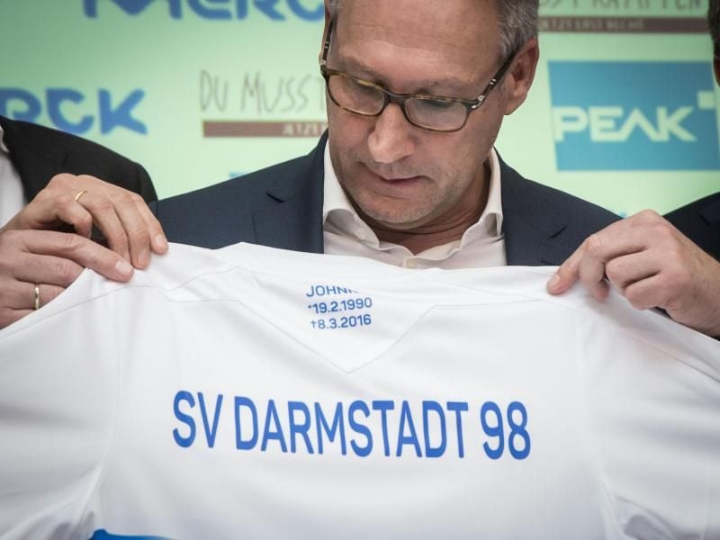 Rüdiger Fritsch, Präsident des SV Darmstadt 98, zeigt ein Sondertrikot zum ersten Todestag von Jonathan „Johnny” Heimes, am Ausschnitt Geburts- und Todesdatum des „Lilien”-Fans, der an einer Krebs-Erkrankung starb. Foto: Frank Rumpenhorst