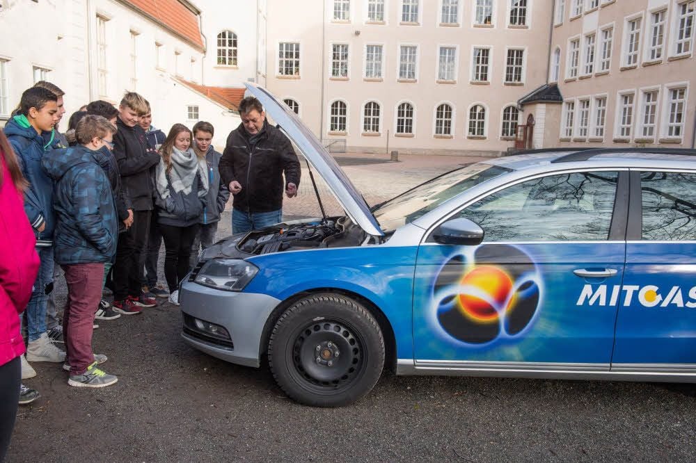 Mit einem Blick unter die Motorhaube seines Firmenwagens versucht Mitgas-Mitarbeiter Thorsten Schack den Schülerinnen und Schülern der 8c die Besonderheiten eines Erdgasauto zu erklären.