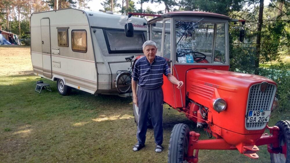 Nicht ohne meinen Trecker. Willy Richter mit Traktor und Wohnanhänger auf dem Campingplatz an den Lausiger Teichen